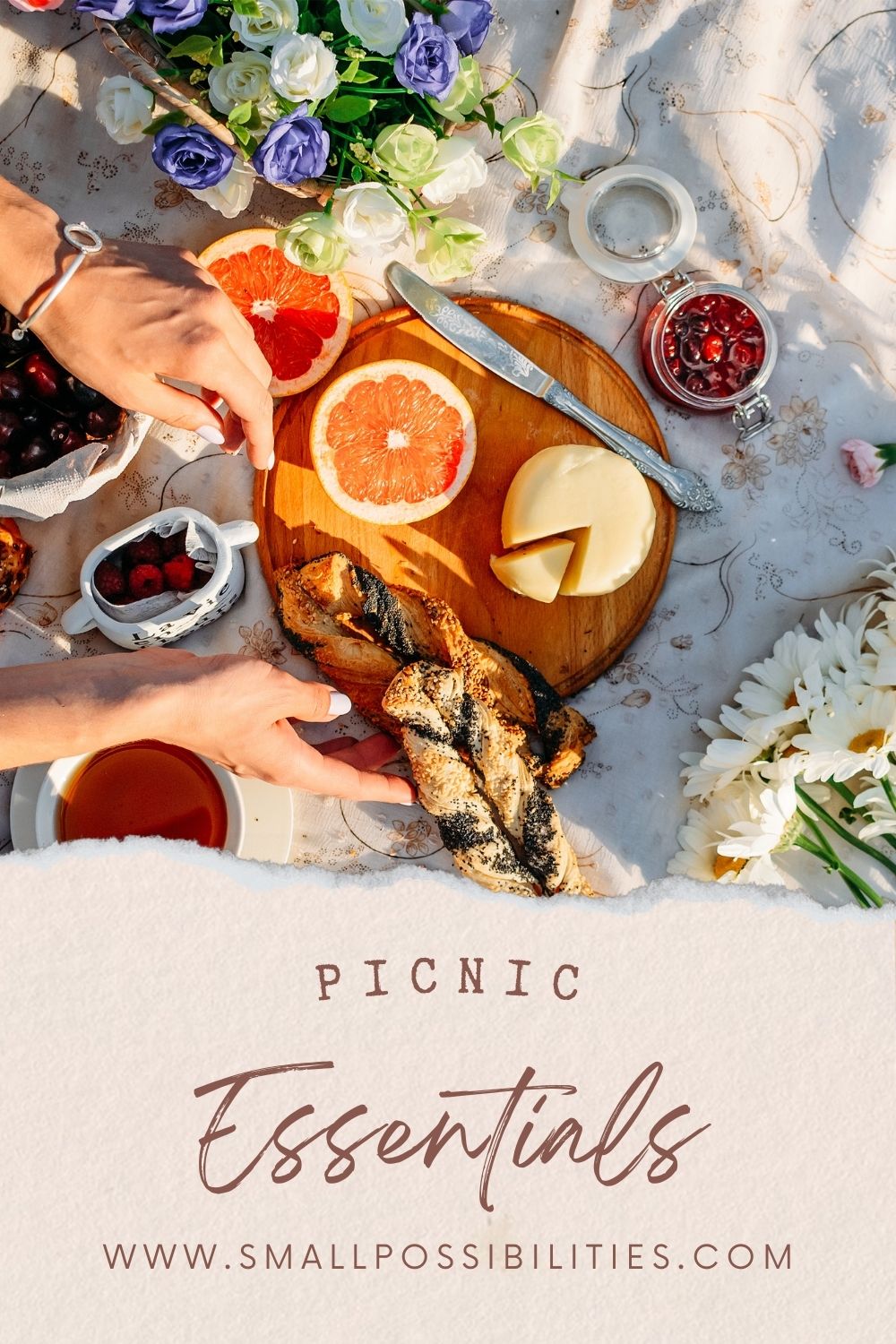 Hands arranging a cozy spring picnic with fresh grapefruit, cheese, crusty bread, and tea on a floral tablecloth surrounded by wildflowers, capturing a slow-living picnic aesthetic and seasonal nourishment.
